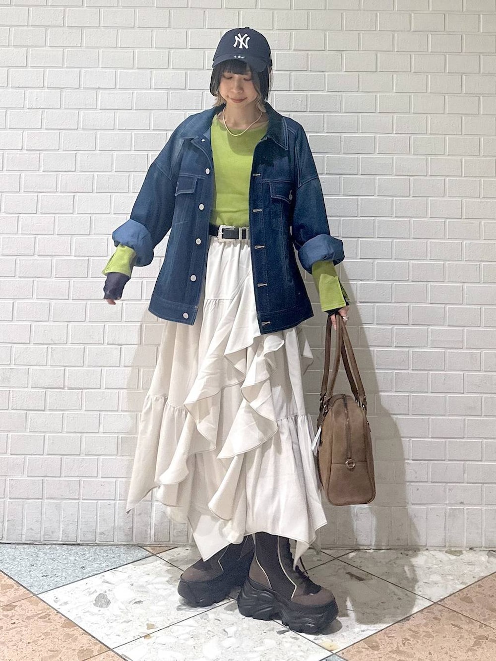 ブラウン系のブーツ、イエロー系のボストンバッグ、ベージュ系のスカートを着用したレディースの冬コーディネートの3枚目の写真