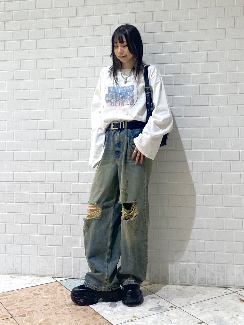 ブラック系のブーツ、ブルー系のデニムパンツ、ブラック系のショルダーバッグを着用したレディースの秋コーディネートの6枚目の写真