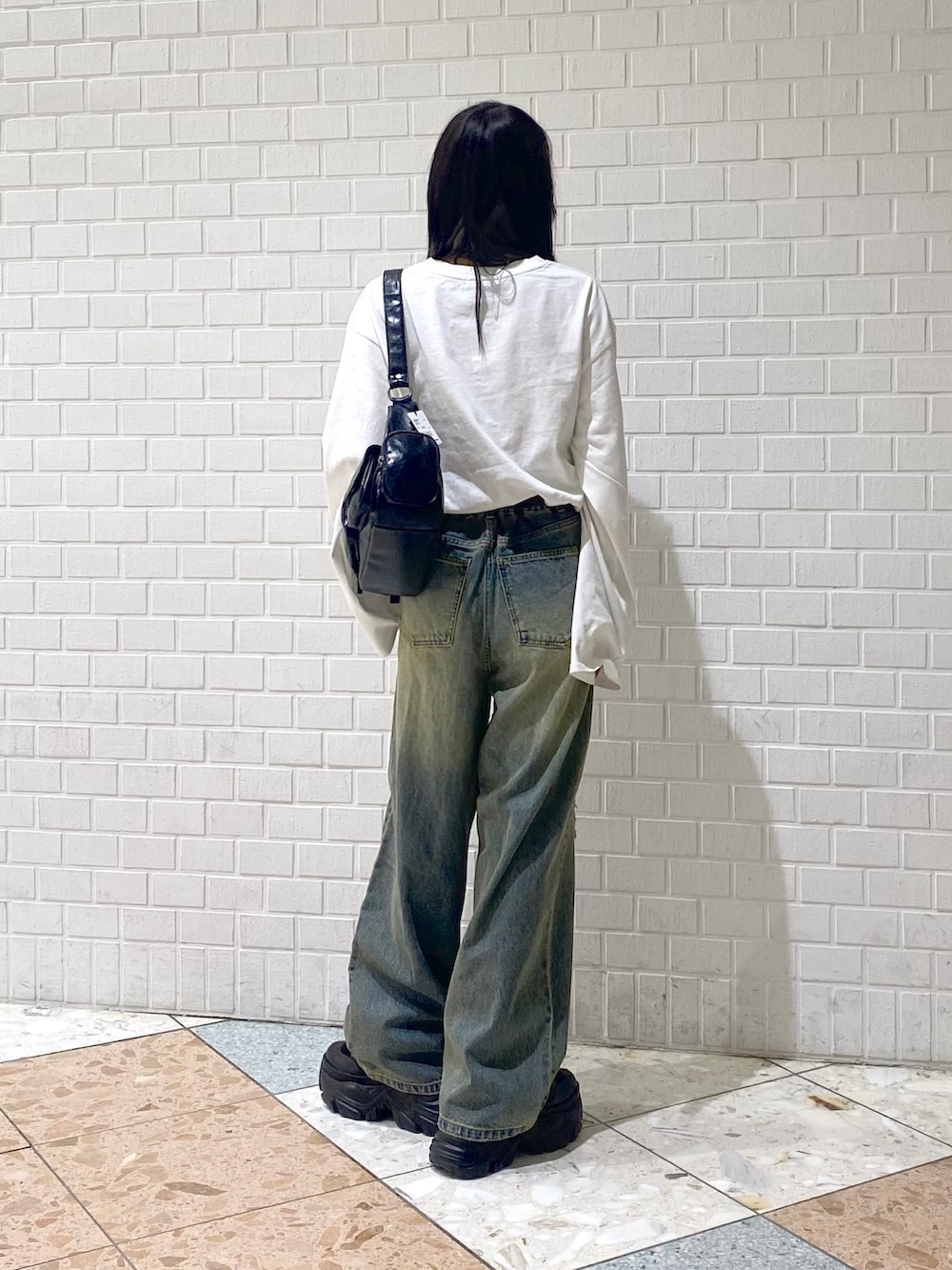 ブラック系のブーツ、ブルー系のデニムパンツ、ブラック系のショルダーバッグを着用したレディースの秋コーディネートの5枚目の写真