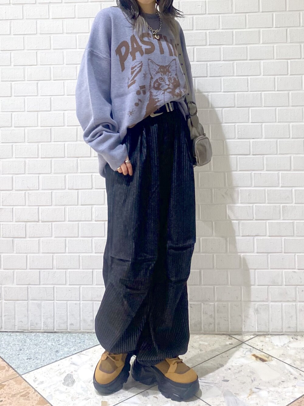 ブラウン系のブーツ、ブラック系のデニムパンツ、シルバー系のショルダーバッグを着用したレディースの冬コーディネートの2枚目の写真