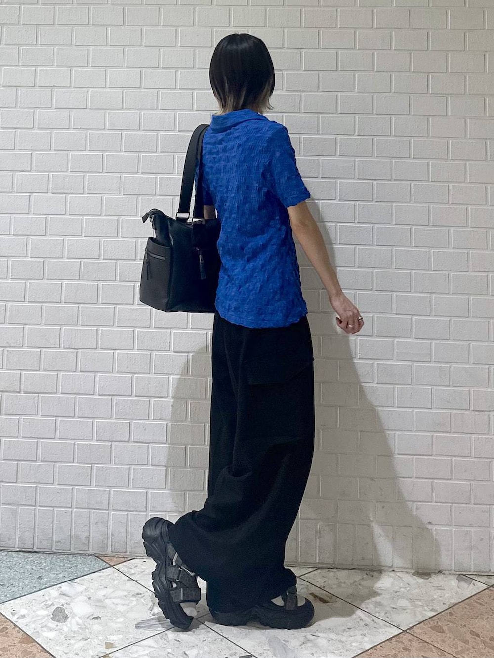 ブラック系のボストンバッグ、グレー系のサンダル、ブラック系のスラックスを着用したレディースの夏コーディネートの7枚目の写真