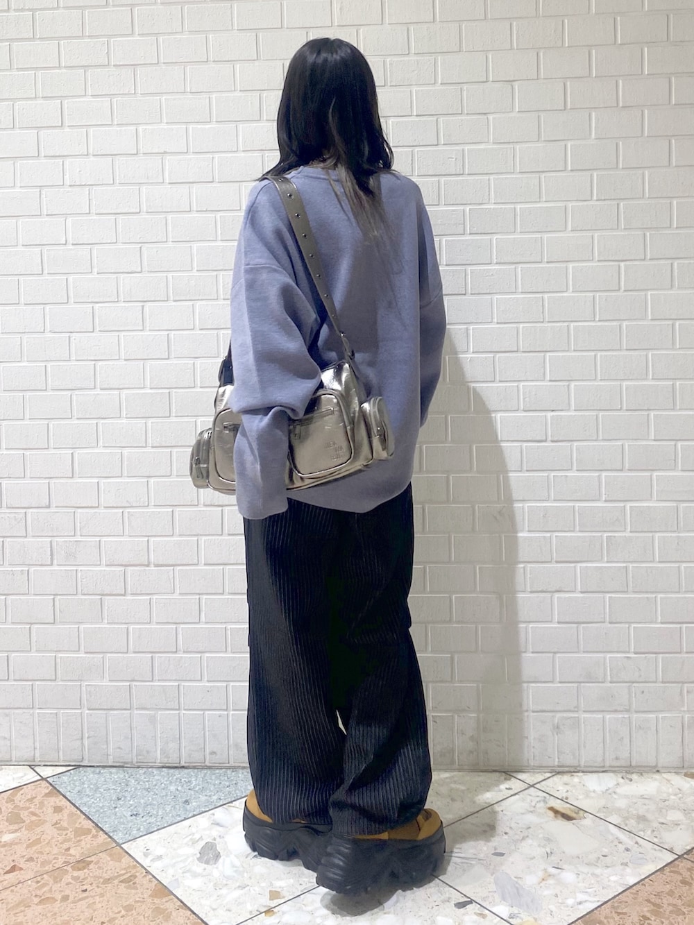 ブラウン系のブーツ、ブラック系のデニムパンツ、シルバー系のショルダーバッグを着用したレディースの冬コーディネートの4枚目の写真