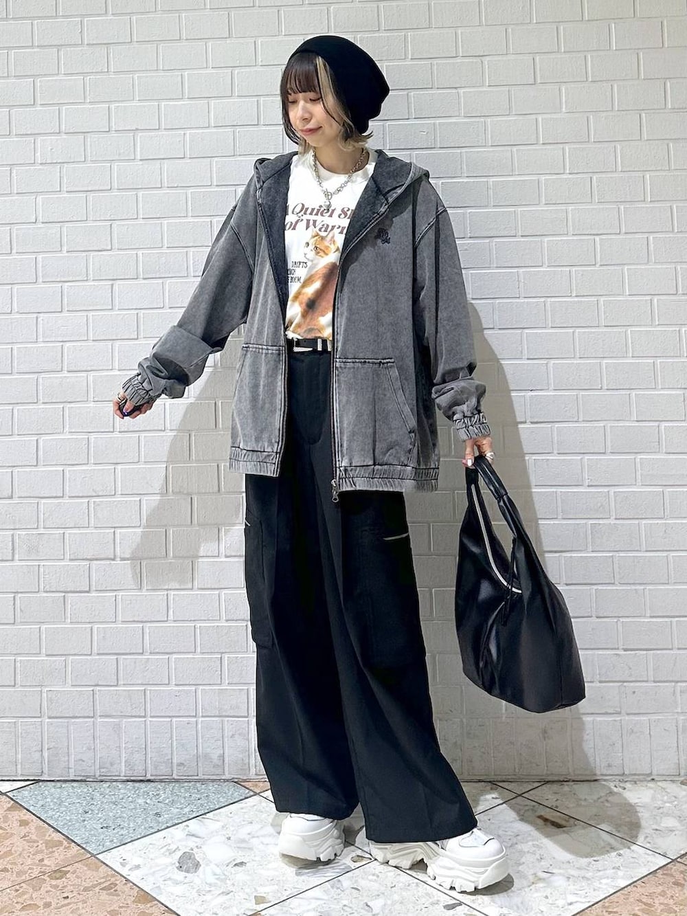 ホワイト系のスニーカー、ブラック系のスラックス、ブラック系のパーカーを着用したレディースの春コーディネートの2枚目の写真