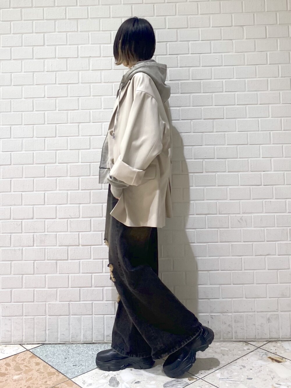 ブラック系のデニムパンツ、ベージュ系のテーラードジャケット、グレー系のパーカーを着用したレディースの冬コーディネートの5枚目の写真