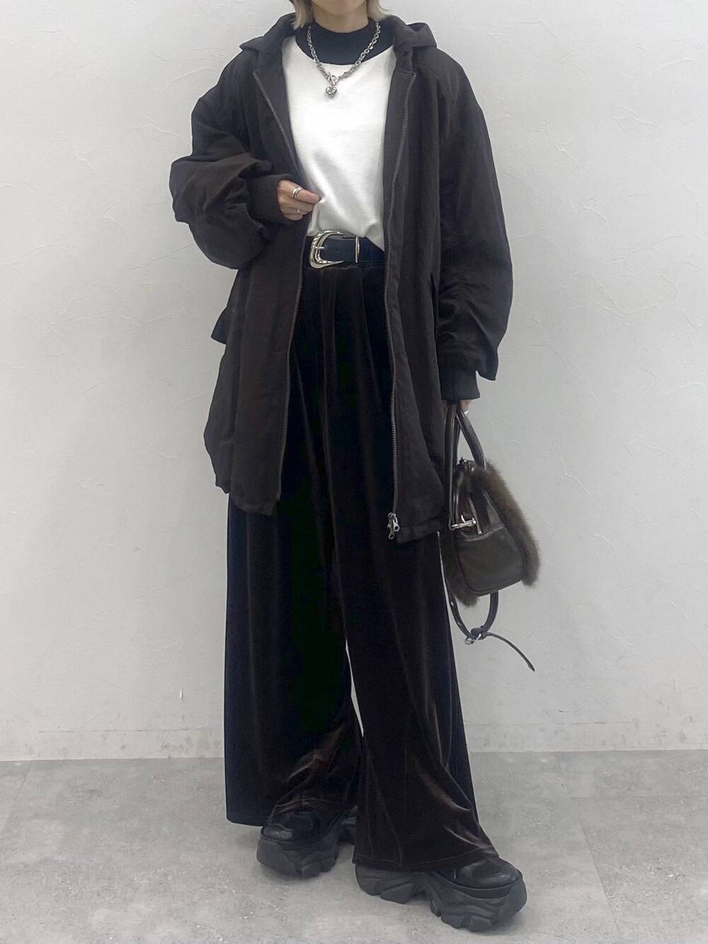 ブラック系のブーツ、ホワイト系のニット/セーター、ブラウン系のブルゾンを着用したレディースの秋コーディネートの2枚目の写真