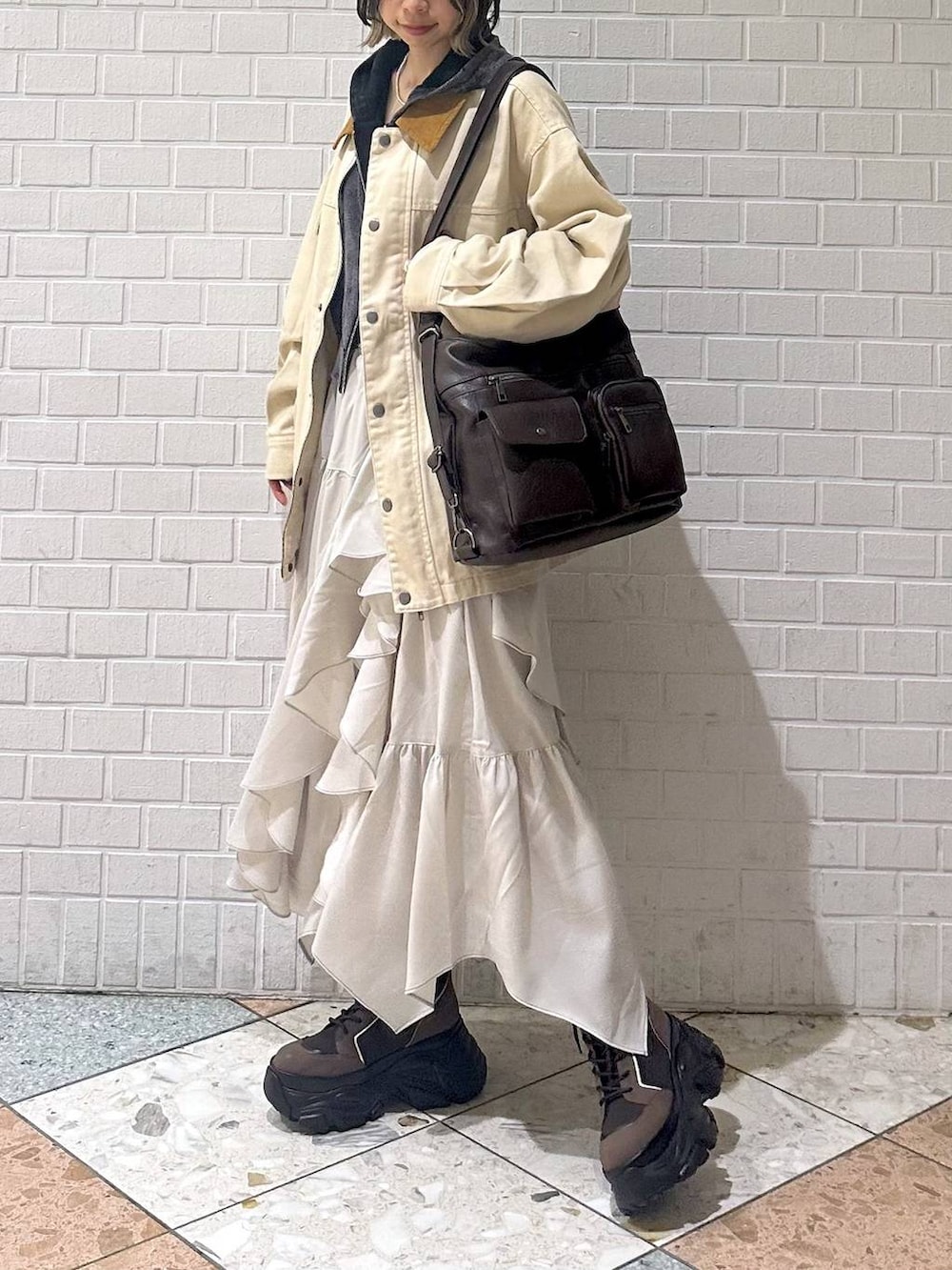 ブラウン系のブーツ、ブラック系のキャミソール、ベージュ系のスカートを着用したレディースの春コーディネートの2枚目の写真