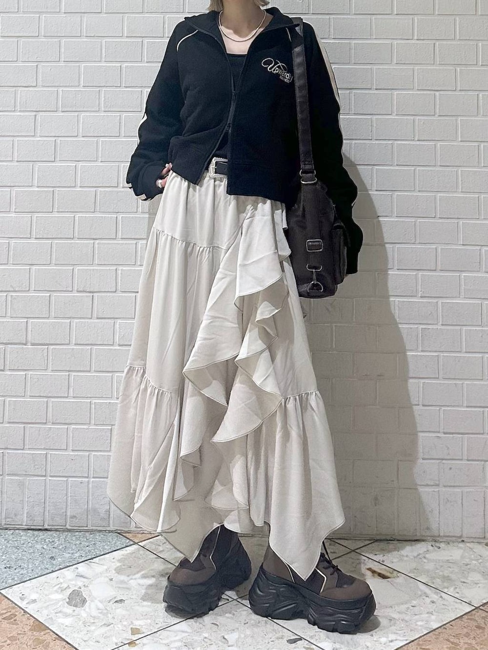 ブラウン系のブーツ、ブラック系のキャミソール、ベージュ系のスカートを着用したレディースの春コーディネートの4枚目の写真