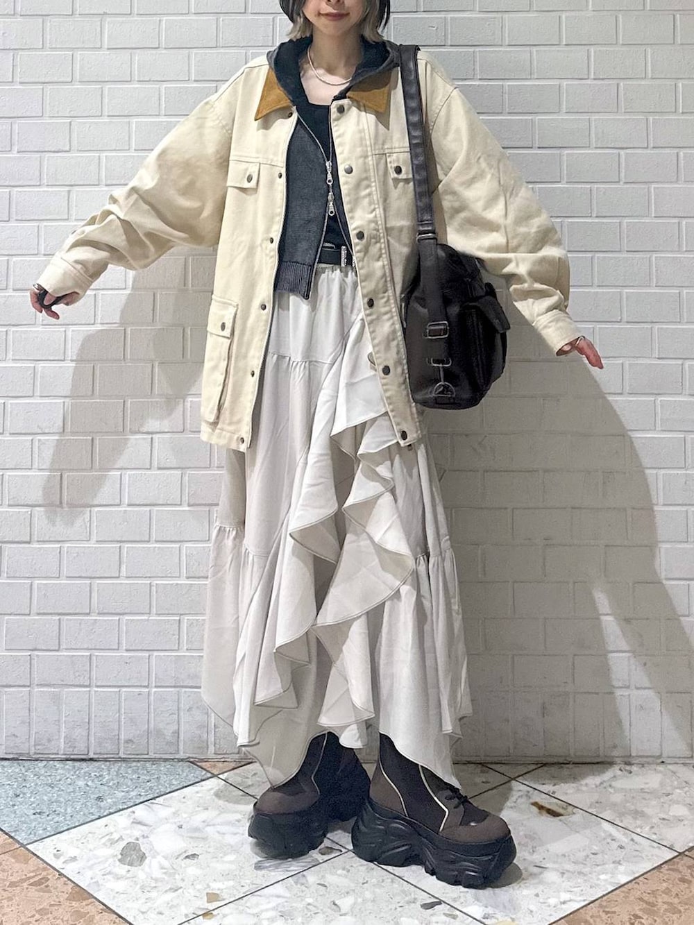 ブラウン系のブーツ、ブラック系のキャミソール、ベージュ系のスカートを着用したレディースの春コーディネートの3枚目の写真