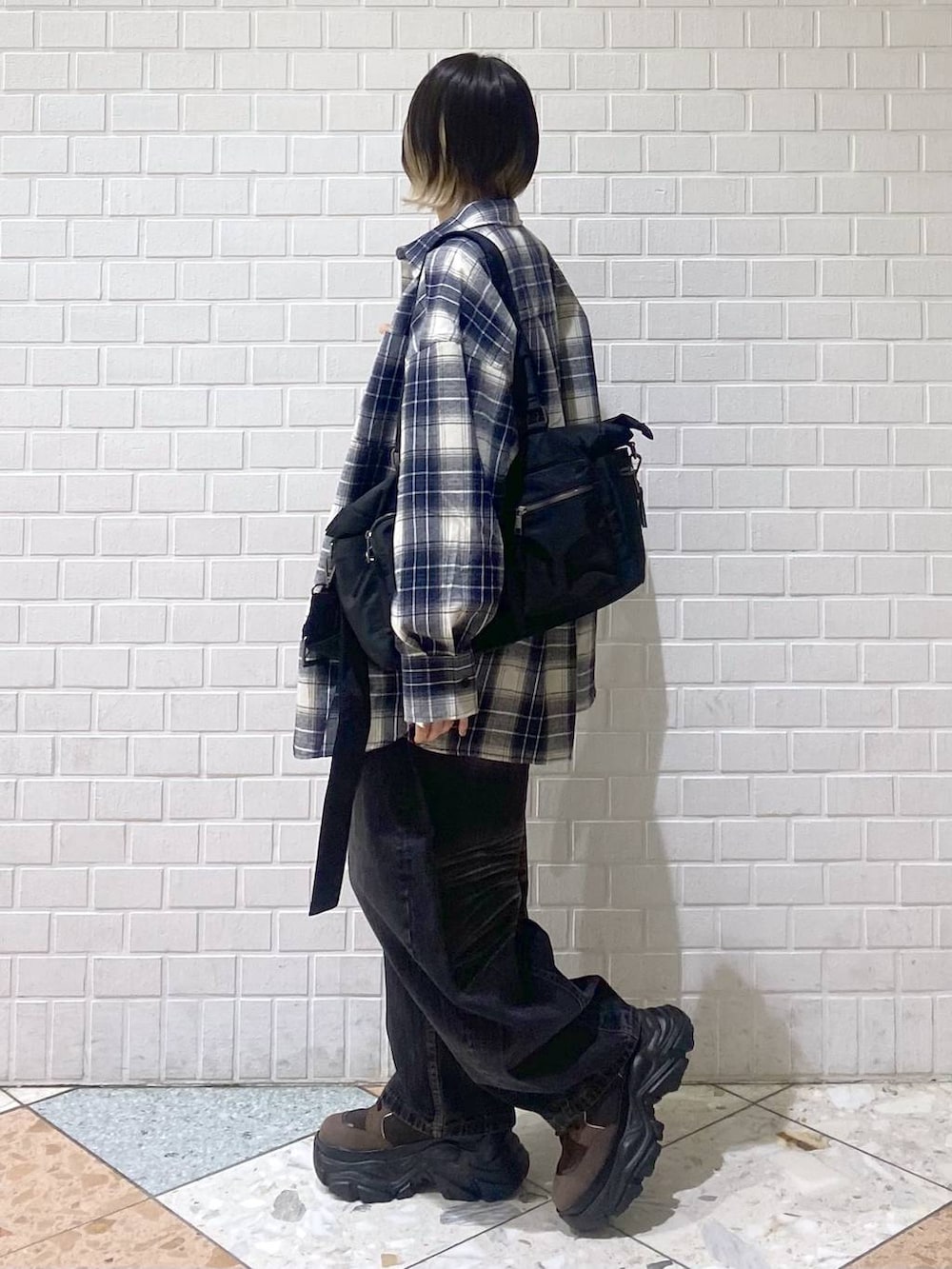 ブラウン系のブーツ、ブラック系のボストンバッグ、ブラック系のデニムパンツを着用したレディースの秋コーディネートの4枚目の写真