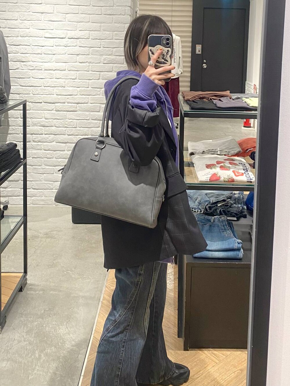 グレー系のボストンバッグ、ブルー系のデニムパンツ、ブラック系のテーラードジャケットを着用したレディースの秋コーディネートの5枚目の写真