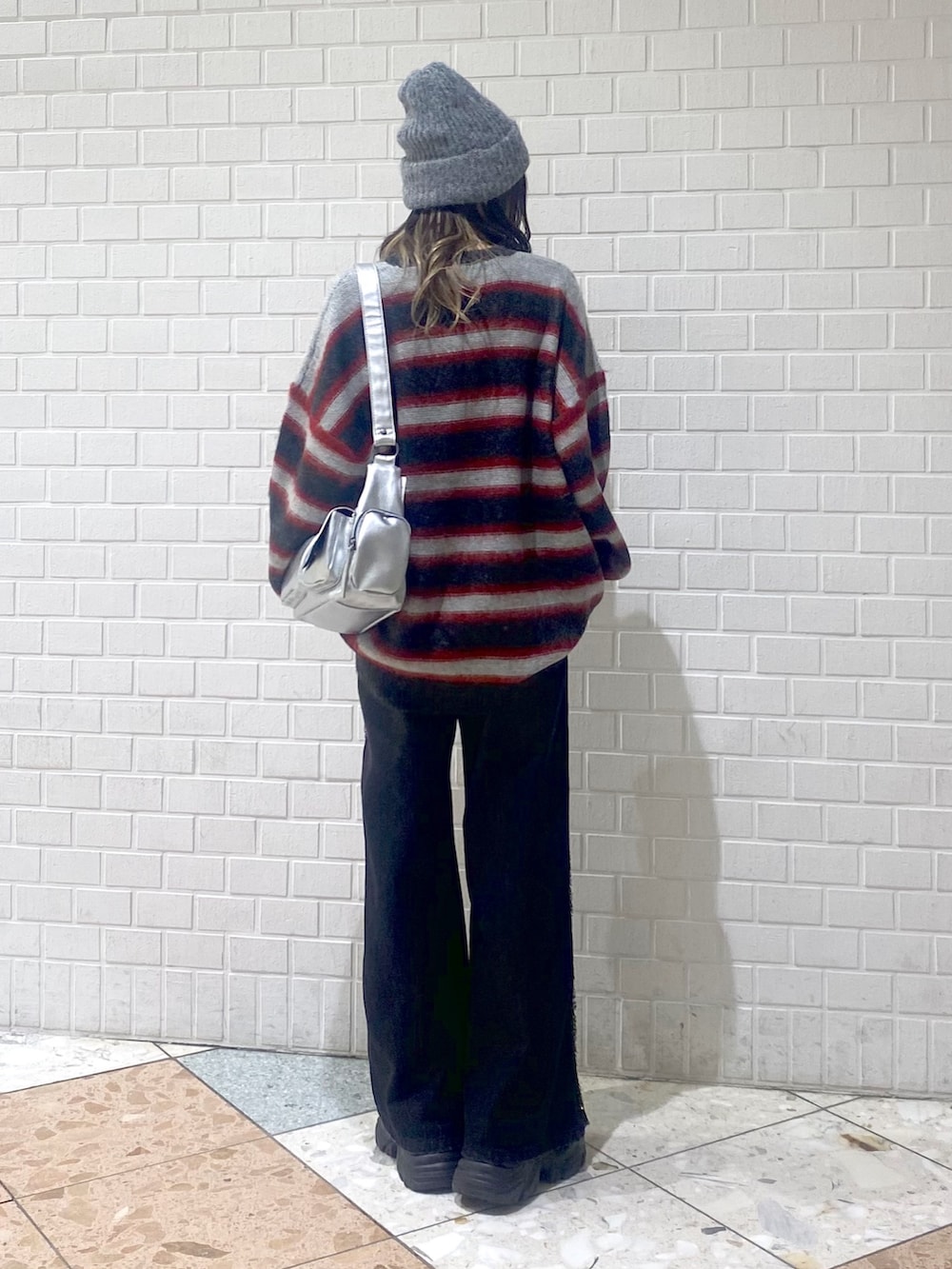 ブラック系のデニムパンツ、ブラック系のブーツ、レッド系のニット/セーターを着用したレディースの秋コーディネートの3枚目の写真