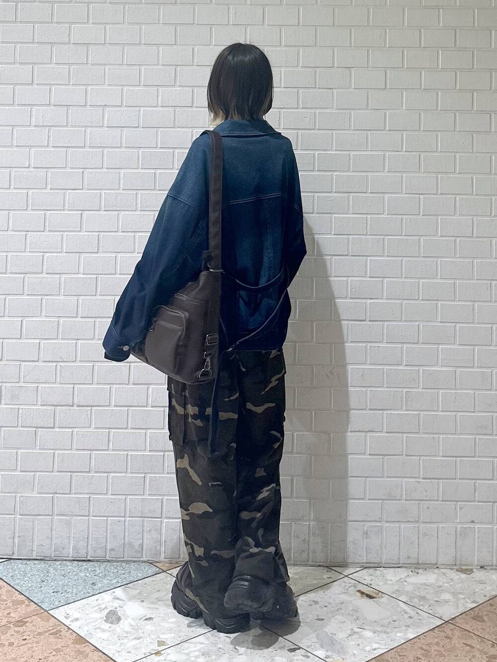 ブラウン系のブーツ、ブラック系のキャミソール、ブルー系のブルゾンを着用したレディースの春コーディネートの7枚目の写真