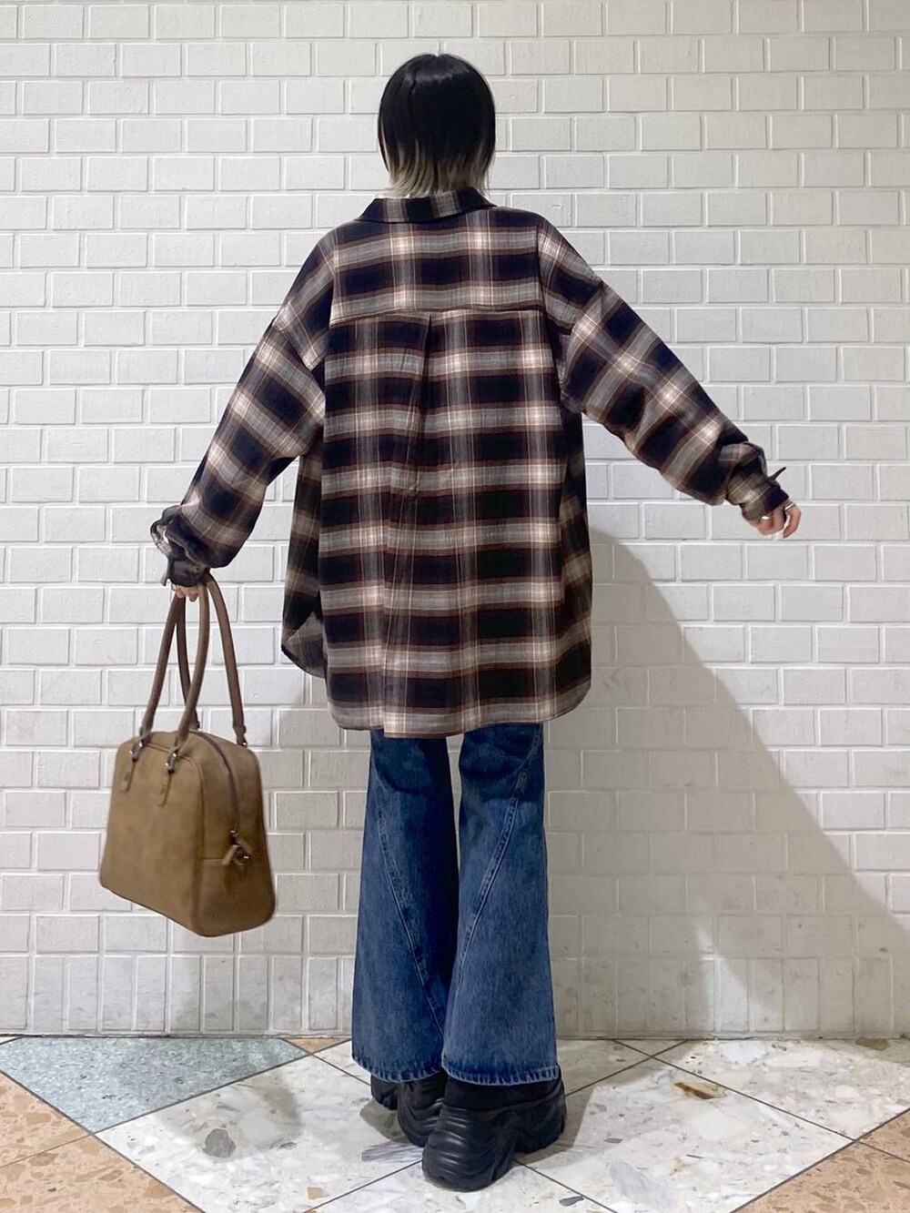 ブラック系のスニーカー、イエロー系のボストンバッグ、ブルー系のデニムパンツを着用したレディースの秋コーディネートの5枚目の写真