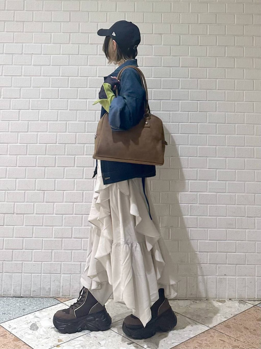 ブラウン系のブーツ、イエロー系のボストンバッグ、ベージュ系のスカートを着用したレディースの冬コーディネートの5枚目の写真