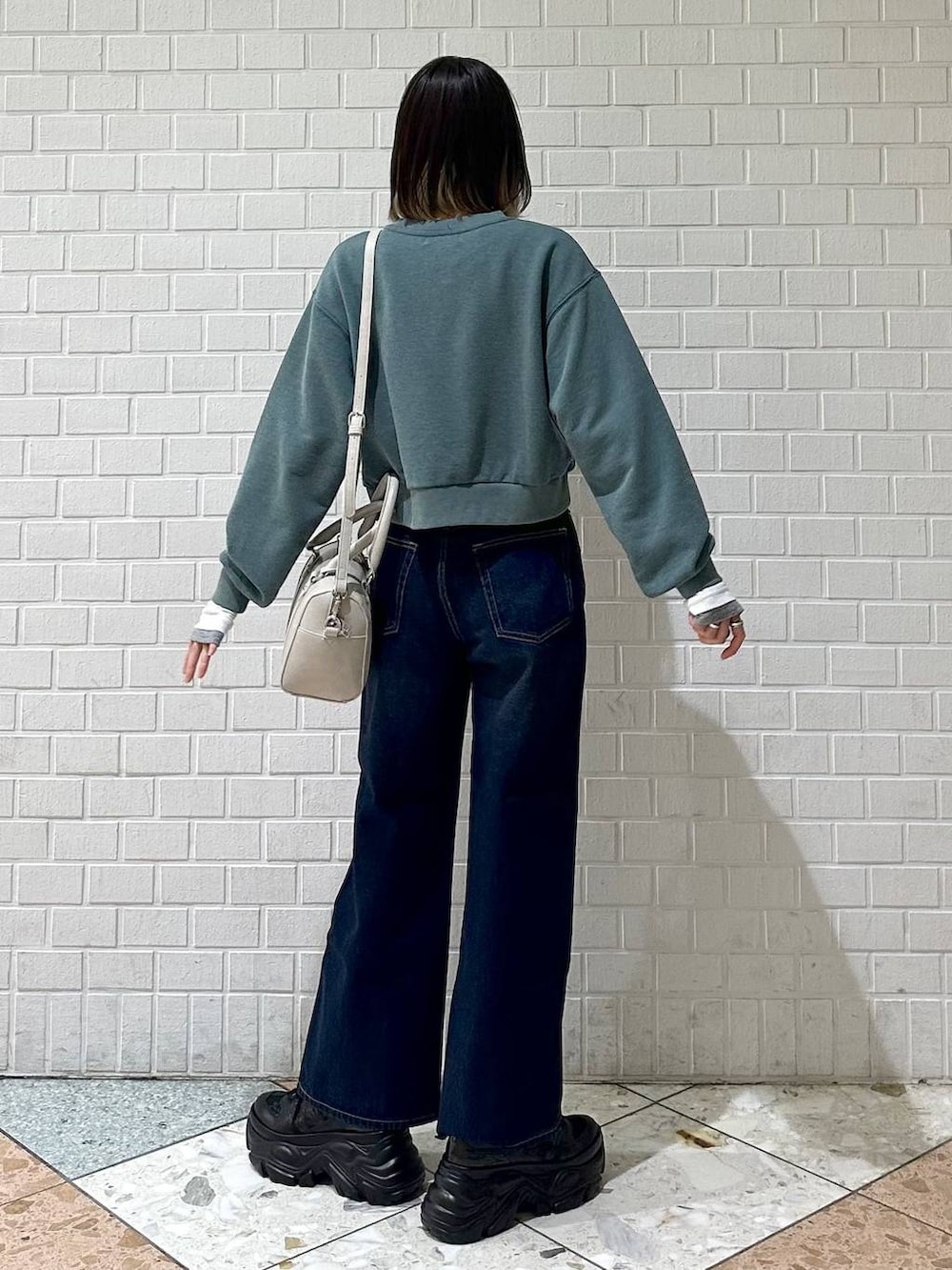 ブラック系のスニーカー、ブルー系のスラックス、ホワイト系のボストンバッグを着用したレディースの冬コーディネートの6枚目の写真