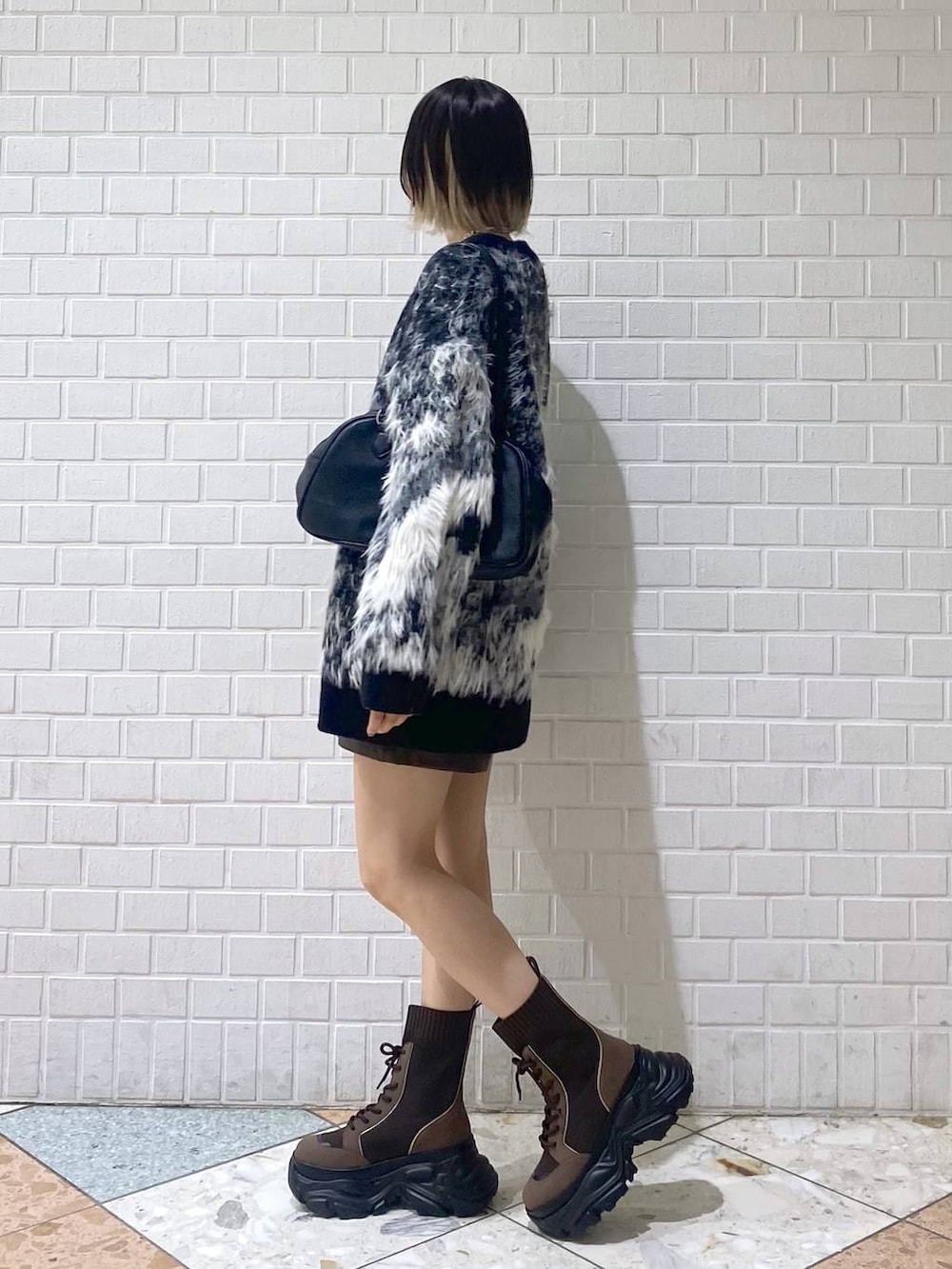 ブラウン系のブーツ、ブラック系のボストンバッグ、レッド系のニット/セーターを着用したレディースの秋コーディネートの4枚目の写真