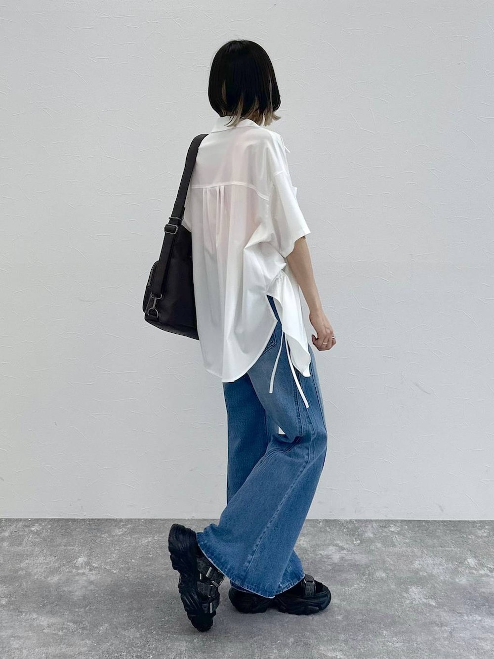 ブルー系のデニムパンツ、ブラック系のショルダーバッグ、グレー系のサンダルを着用したレディースの春コーディネートの8枚目の写真