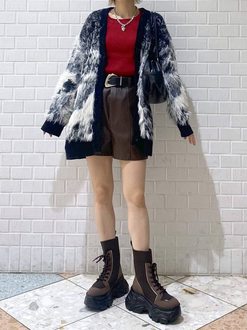 ブラウン系のブーツ、ブラック系のボストンバッグ、レッド系のニット/セーターを着用したレディースの秋コーディネートの9枚目の写真