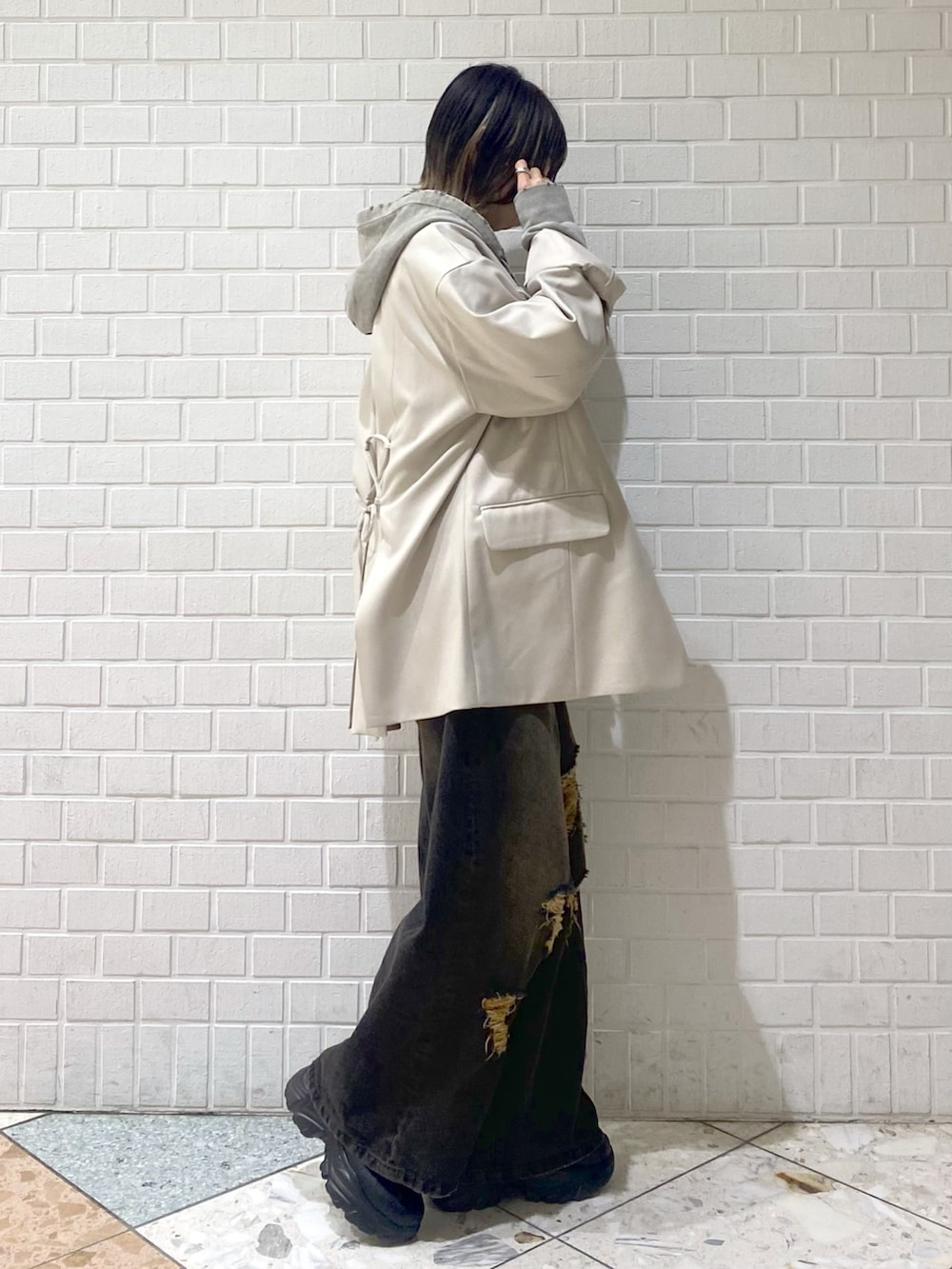 ブラック系のデニムパンツ、ベージュ系のテーラードジャケット、グレー系のパーカーを着用したレディースの冬コーディネートの3枚目の写真