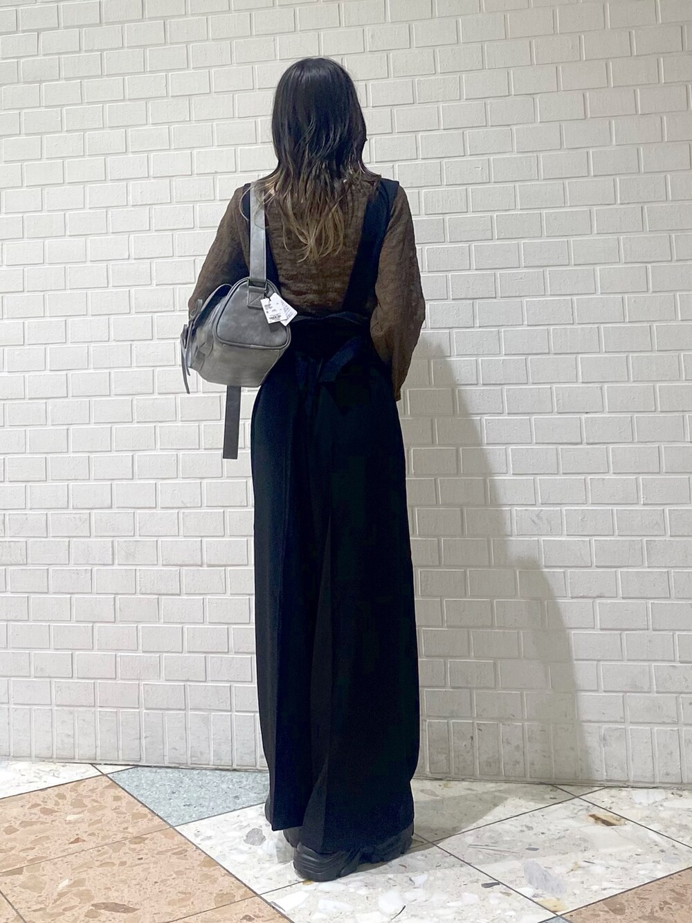 ブラック系のブーツ、ブラック系のスラックス、ブラウン系のTシャツ/カットソーを着用したレディースの秋コーディネートの4枚目の写真