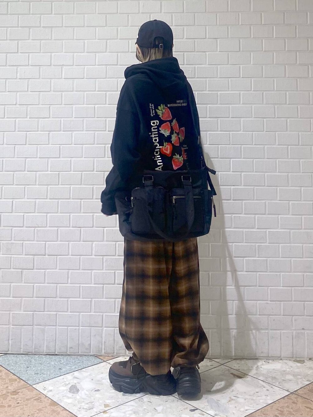 ブラウン系のブーツ、ブラック系のボストンバッグ、ブラック系のパーカーを着用したレディースの秋コーディネートの3枚目の写真