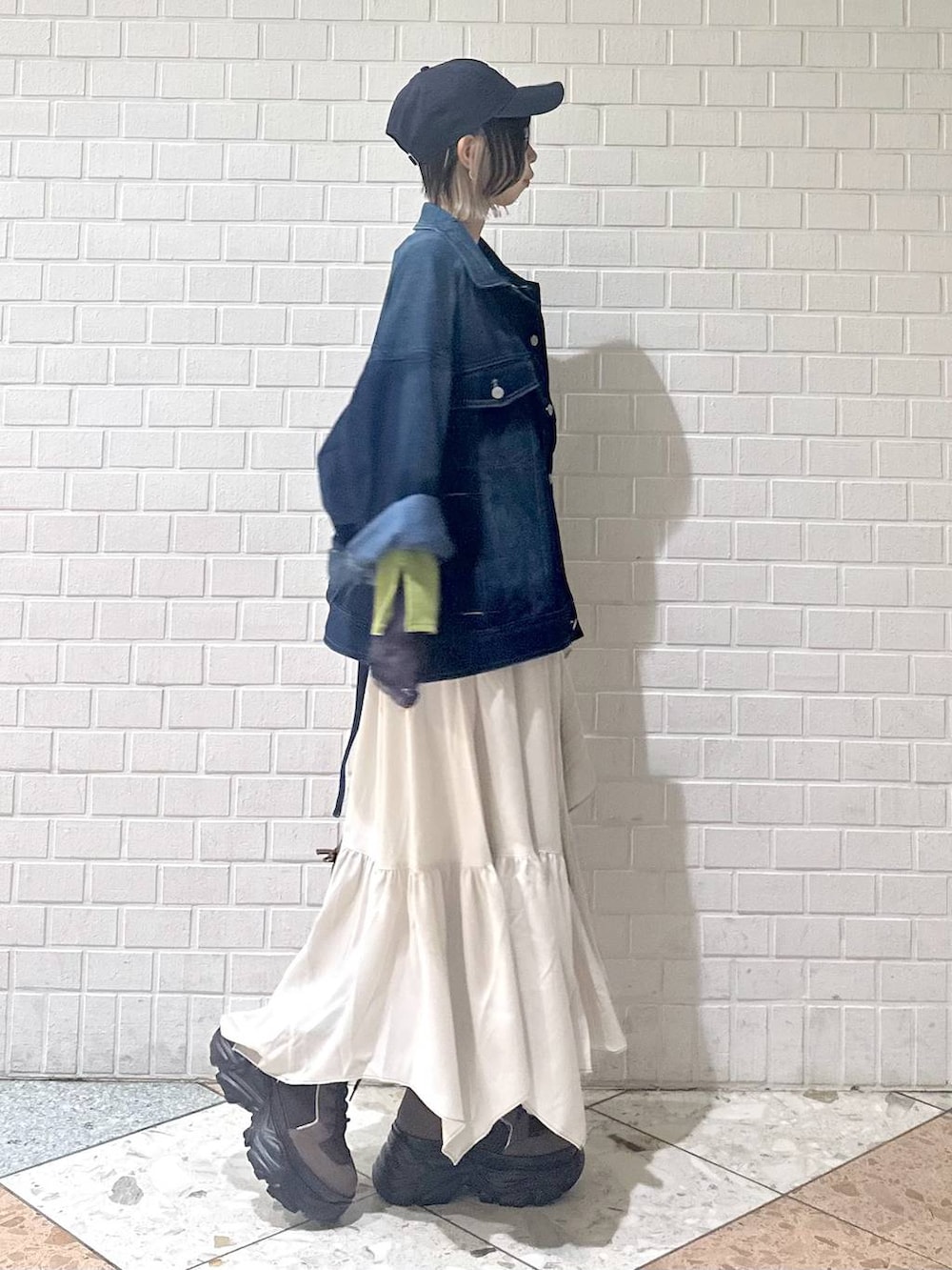 ブラウン系のブーツ、イエロー系のボストンバッグ、ベージュ系のスカートを着用したレディースの冬コーディネートの8枚目の写真