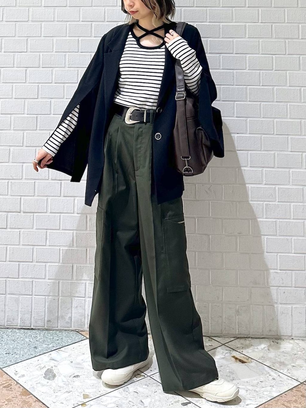 ブラック系のテーラードジャケット、ホワイト系のスニーカー、グリーン系のスラックスを着用したレディースの冬コーディネートの3枚目の写真