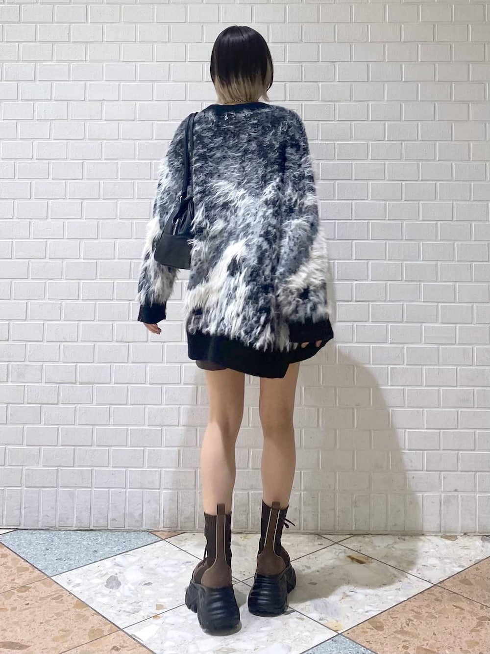 ブラウン系のブーツ、ブラック系のボストンバッグ、レッド系のニット/セーターを着用したレディースの秋コーディネートの5枚目の写真