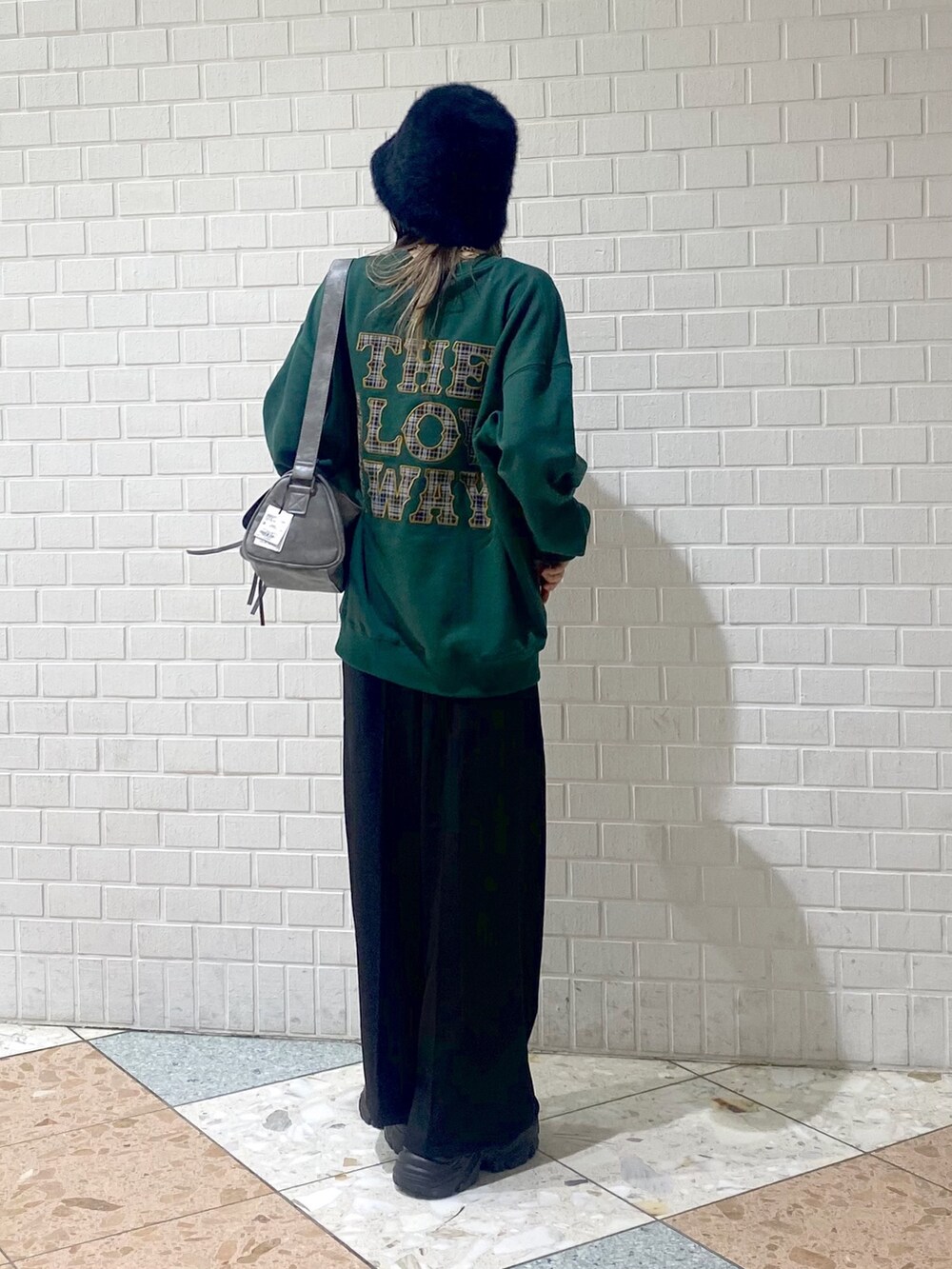 ブラック系のブーツ、ブラック系のスラックス、グレー系のショルダーバッグを着用したレディースの秋コーディネートの4枚目の写真