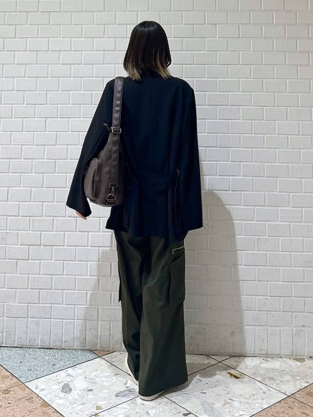 ブラック系のテーラードジャケット、ホワイト系のスニーカー、グリーン系のスラックスを着用したレディースの冬コーディネートの5枚目の写真