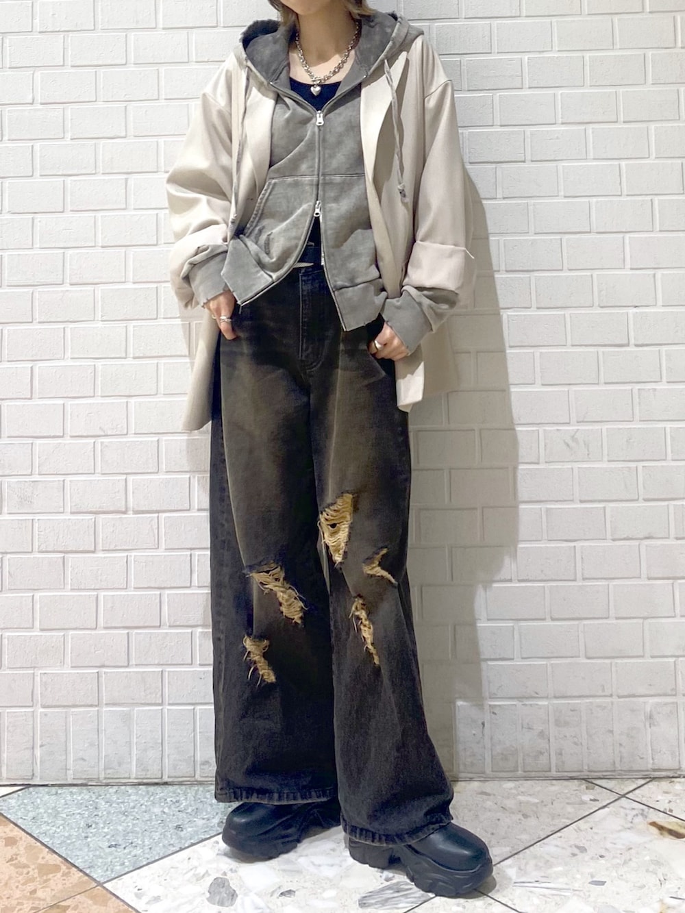 ブラック系のデニムパンツ、ベージュ系のテーラードジャケット、グレー系のパーカーを着用したレディースの冬コーディネートの2枚目の写真