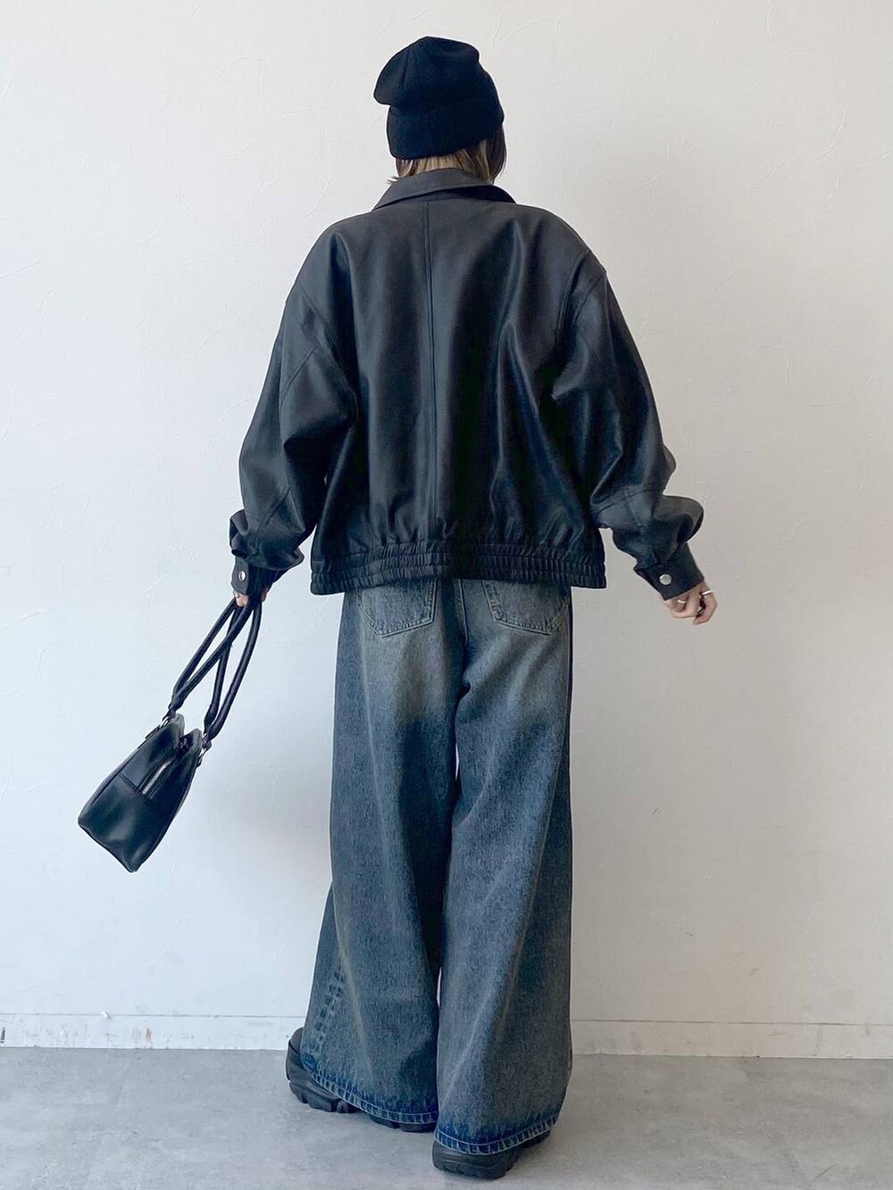 ブラック系のスニーカー、ブルー系のデニムパンツ、ブラック系のブルゾンを着用したレディースの夏コーディネートの5枚目の写真