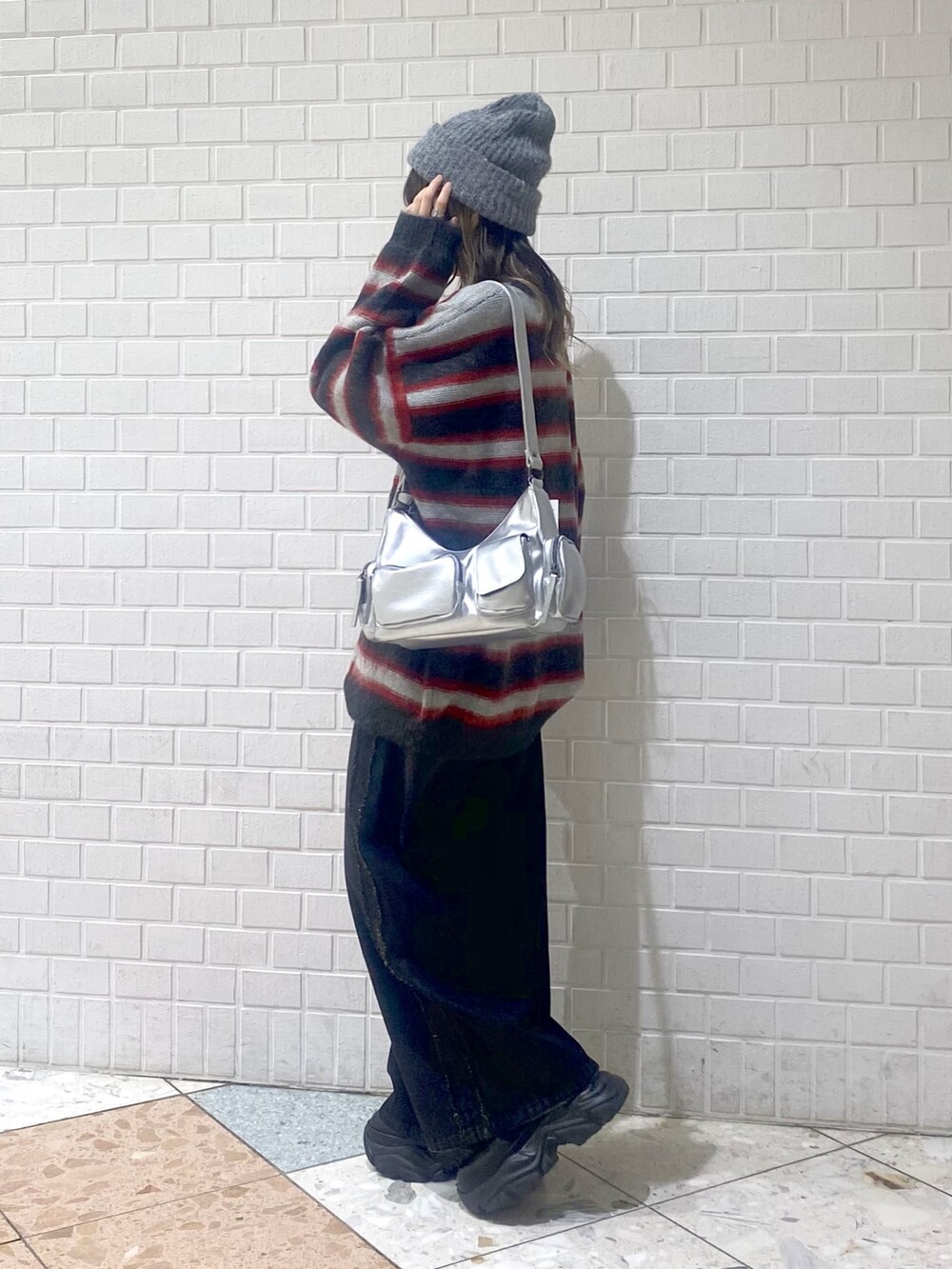 ブラック系のデニムパンツ、ブラック系のブーツ、レッド系のニット/セーターを着用したレディースの秋コーディネートの2枚目の写真