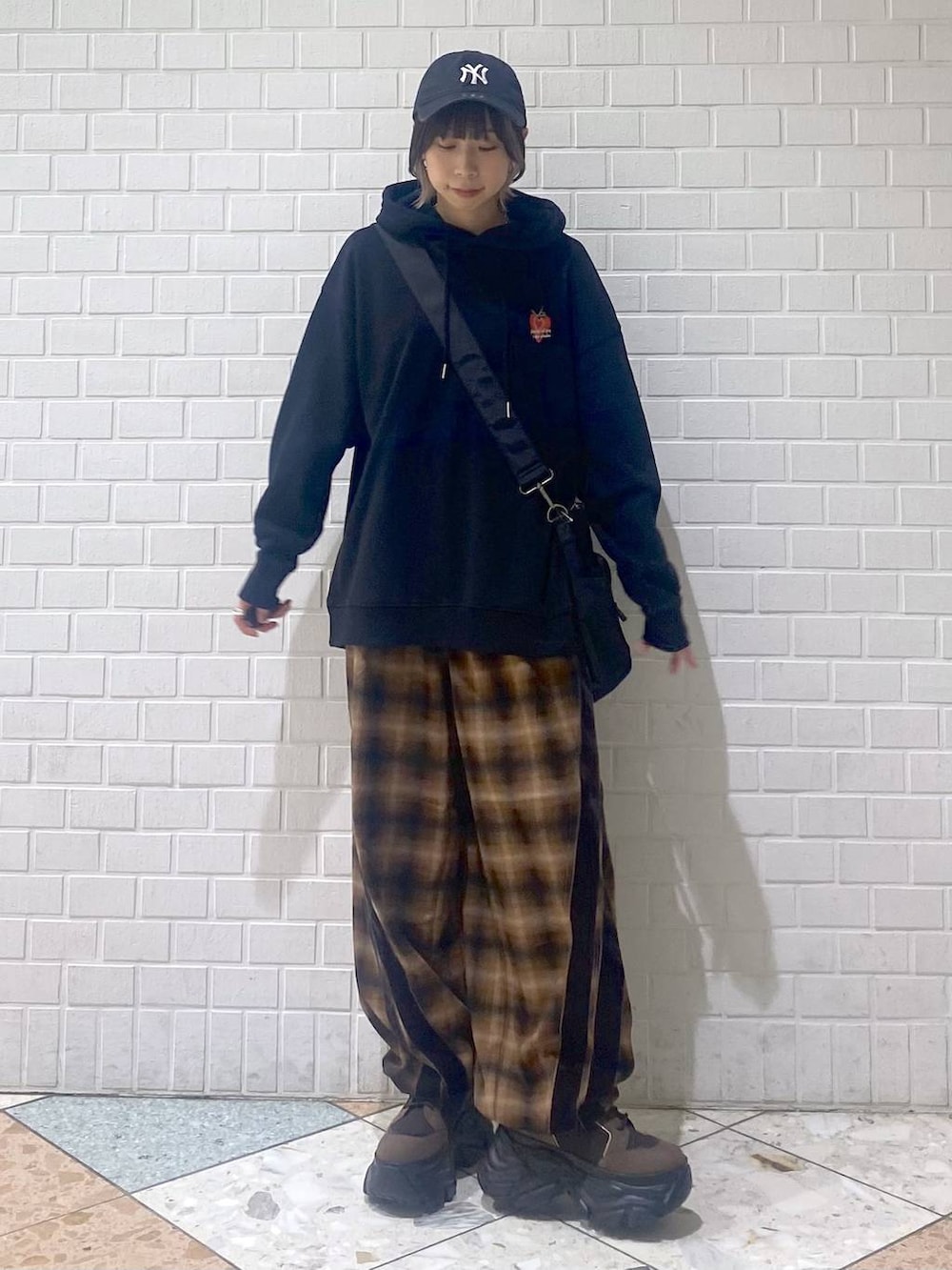 ブラウン系のブーツ、ブラック系のボストンバッグ、ブラック系のパーカーを着用したレディースの秋コーディネートの4枚目の写真