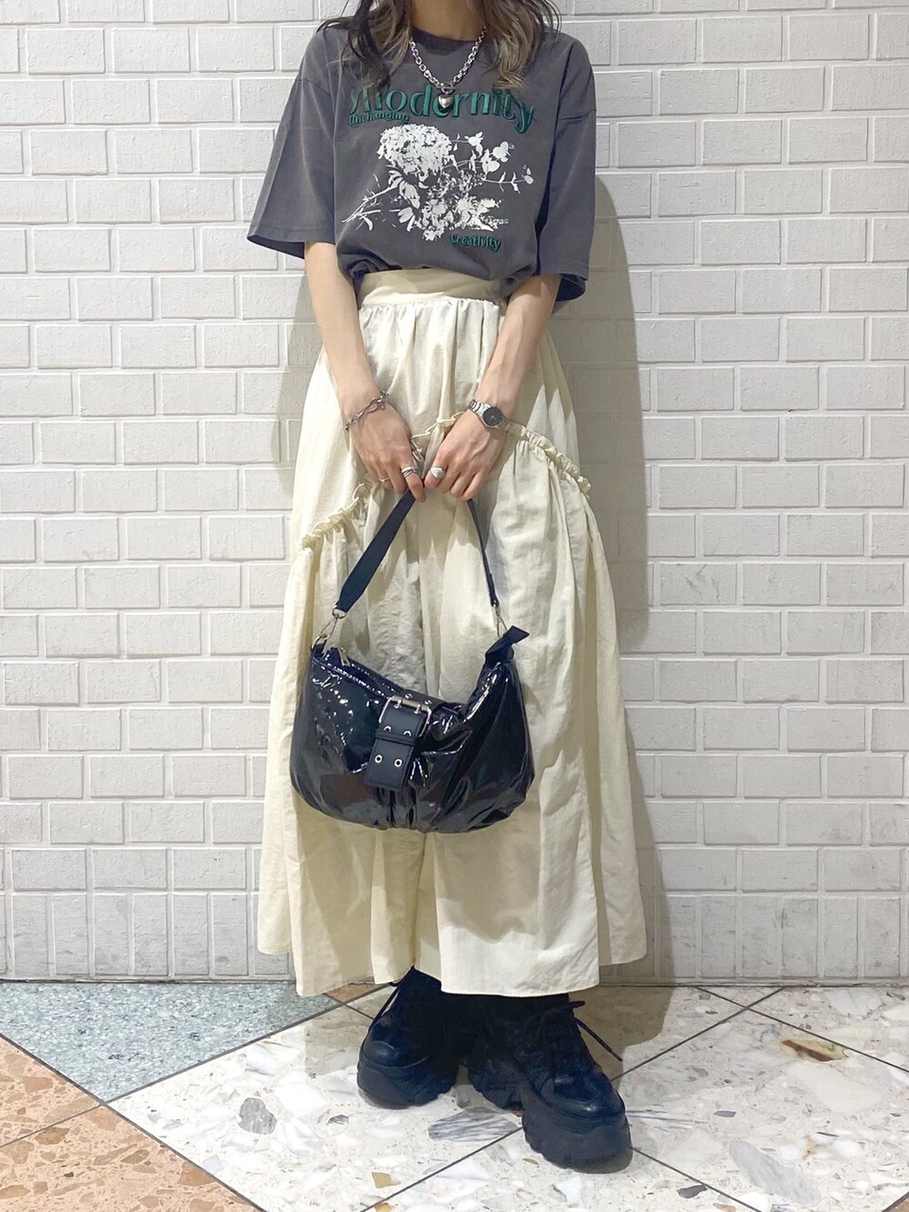 ブラック系のショルダーバッグ、ブラック系のスニーカー、ホワイト系のスカートを着用したレディースの夏コーディネートの7枚目の写真