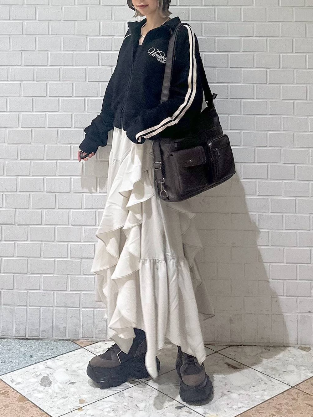 ブラウン系のブーツ、ブラック系のキャミソール、ベージュ系のスカートを着用したレディースの春コーディネートの2枚目の写真