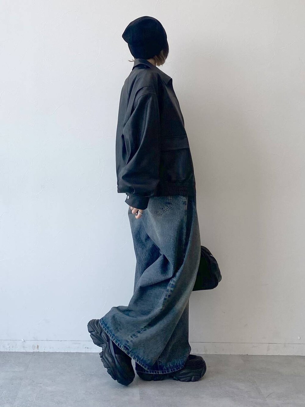 ブラック系のスニーカー、ブルー系のデニムパンツ、ブラック系のブルゾンを着用したレディースの夏コーディネートの6枚目の写真