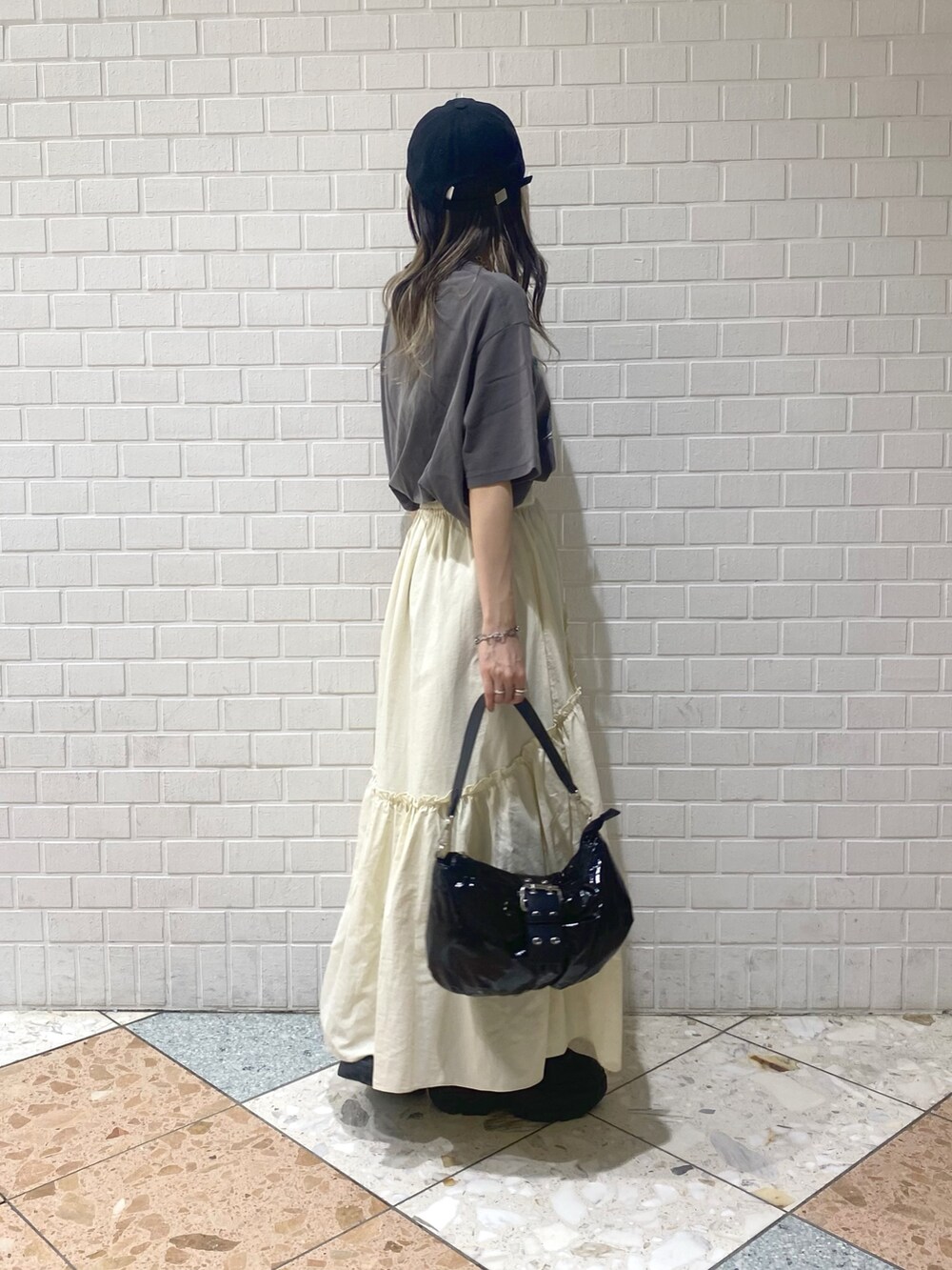 ブラック系のショルダーバッグ、ブラック系のスニーカー、ホワイト系のスカートを着用したレディースの夏コーディネートの5枚目の写真