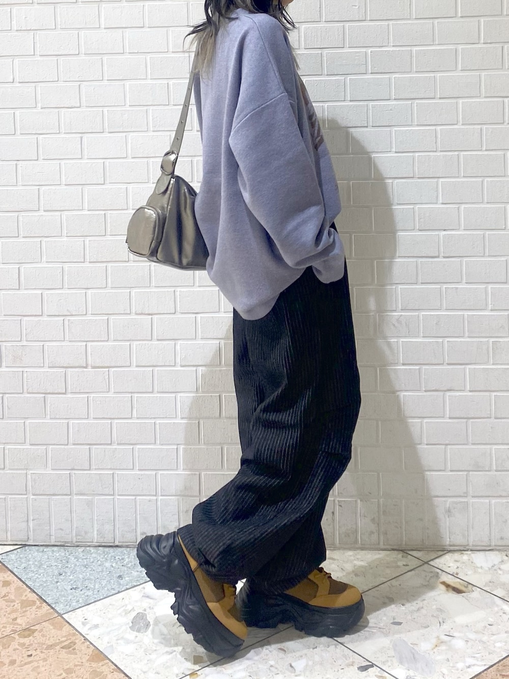 ブラウン系のブーツ、ブラック系のデニムパンツ、シルバー系のショルダーバッグを着用したレディースの冬コーディネートの3枚目の写真