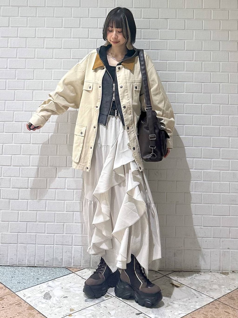 ブラウン系のブーツ、ブラック系のキャミソール、ベージュ系のスカートを着用したレディースの春コーディネートの4枚目の写真