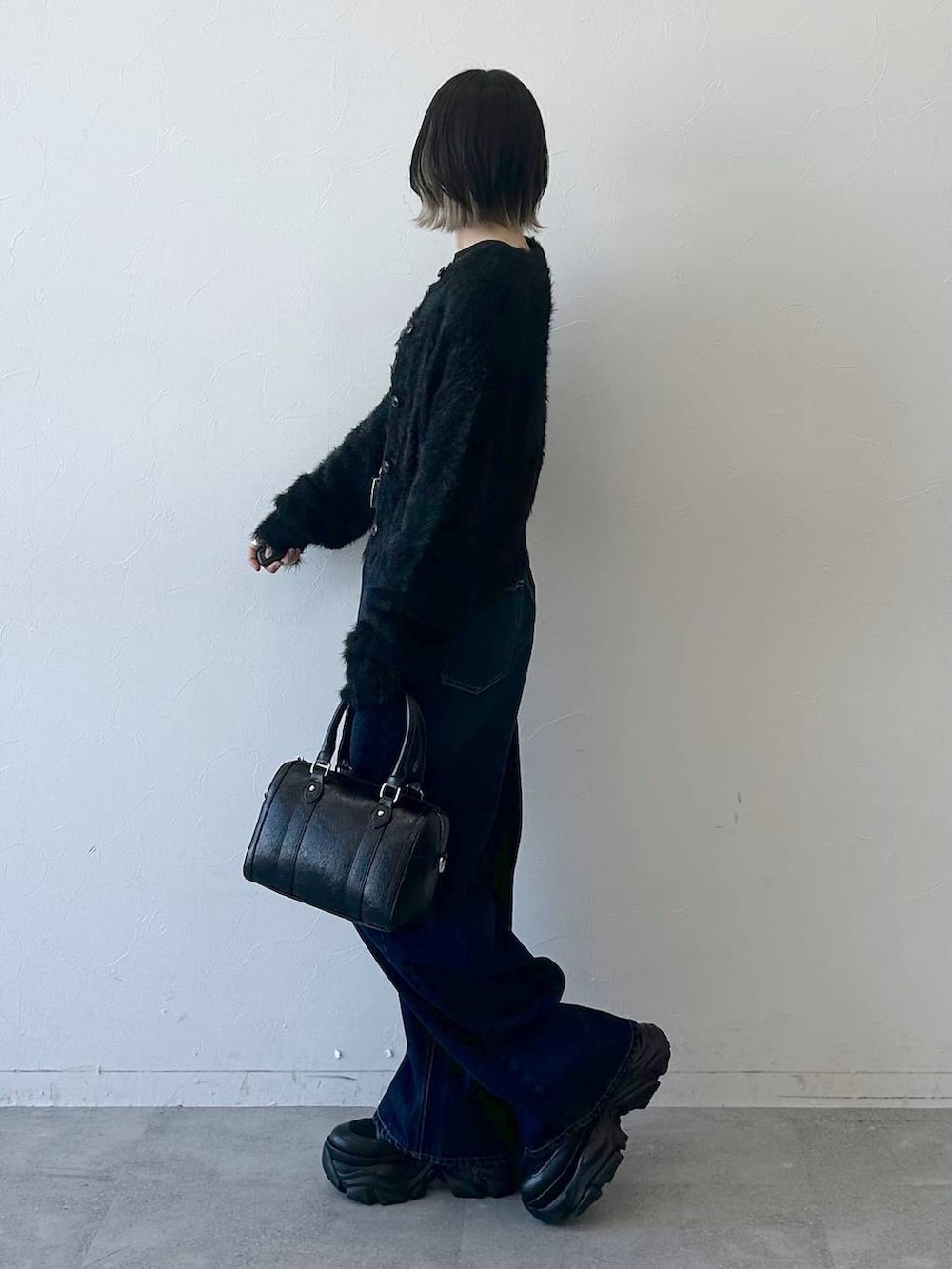 ブラック系のブーツ、ブルー系のスラックス、ブラック系のボストンバッグを着用したレディースの冬コーディネートの5枚目の写真