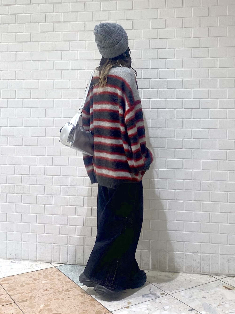 ブラック系のデニムパンツ、ブラック系のブーツ、レッド系のニット/セーターを着用したレディースの秋コーディネートの4枚目の写真