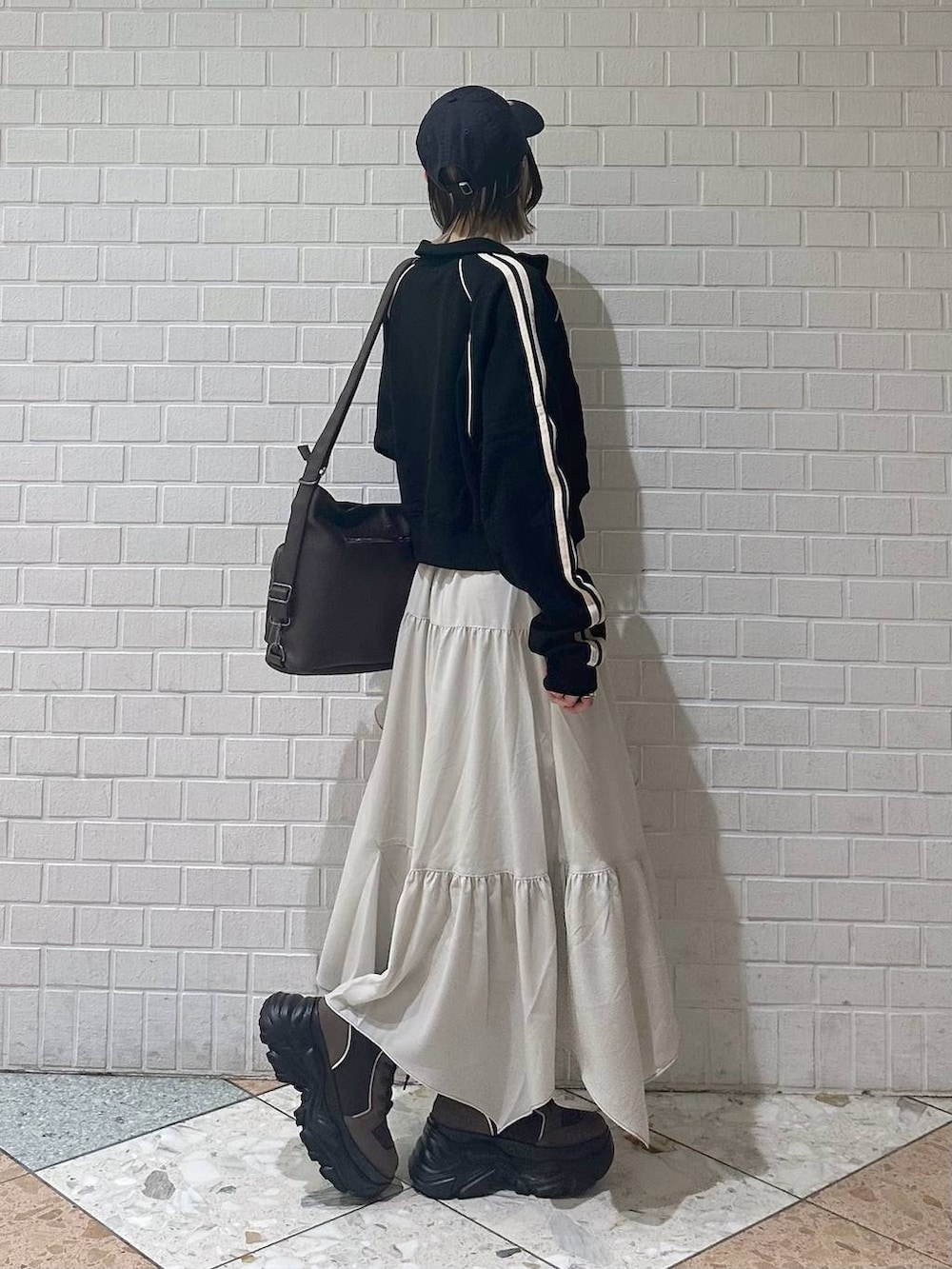 ブラウン系のブーツ、ブラック系のキャミソール、ベージュ系のスカートを着用したレディースの春コーディネートの7枚目の写真