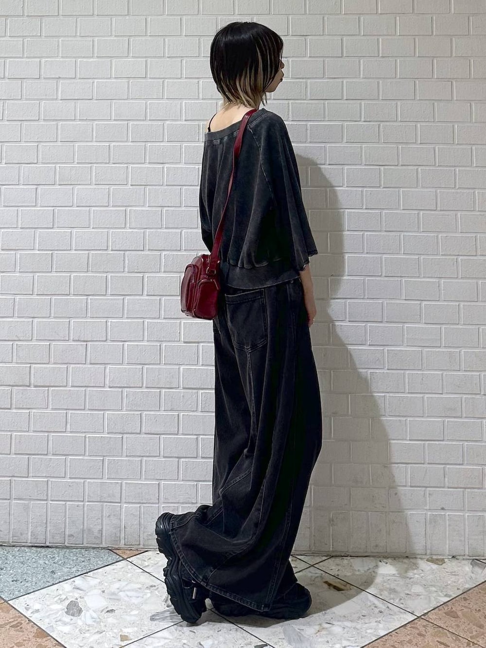 ブラック系のデニムパンツ、ブラック系のTシャツ/カットソー、レッド系のショルダーバッグを着用したレディースの夏コーディネートの7枚目の写真