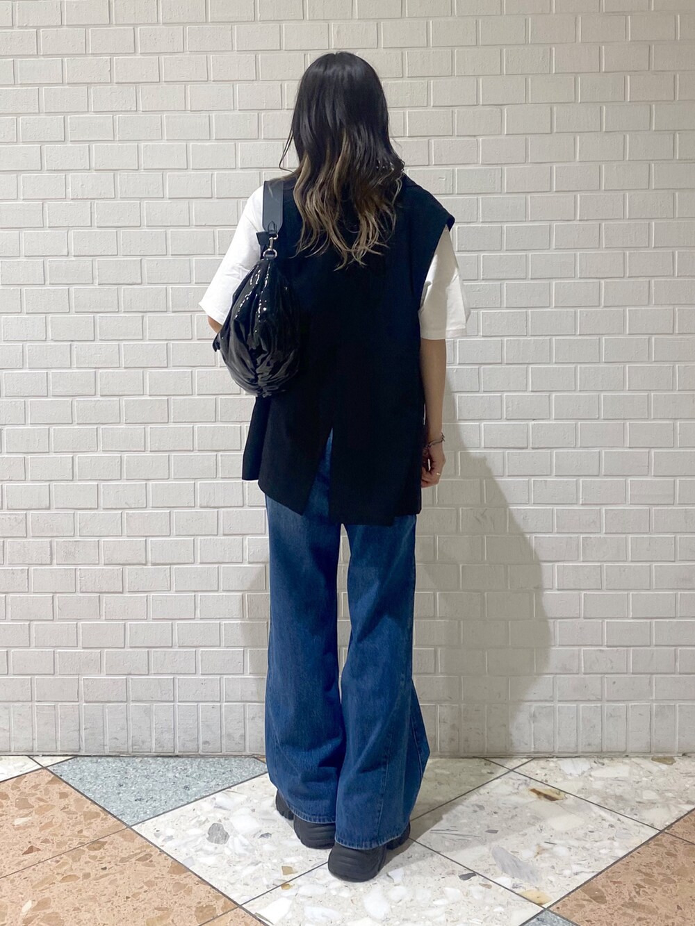 ブルー系のデニムパンツ、ブラック系のスニーカー、ブラック系のショルダーバッグを着用したレディースの秋コーディネートの3枚目の写真