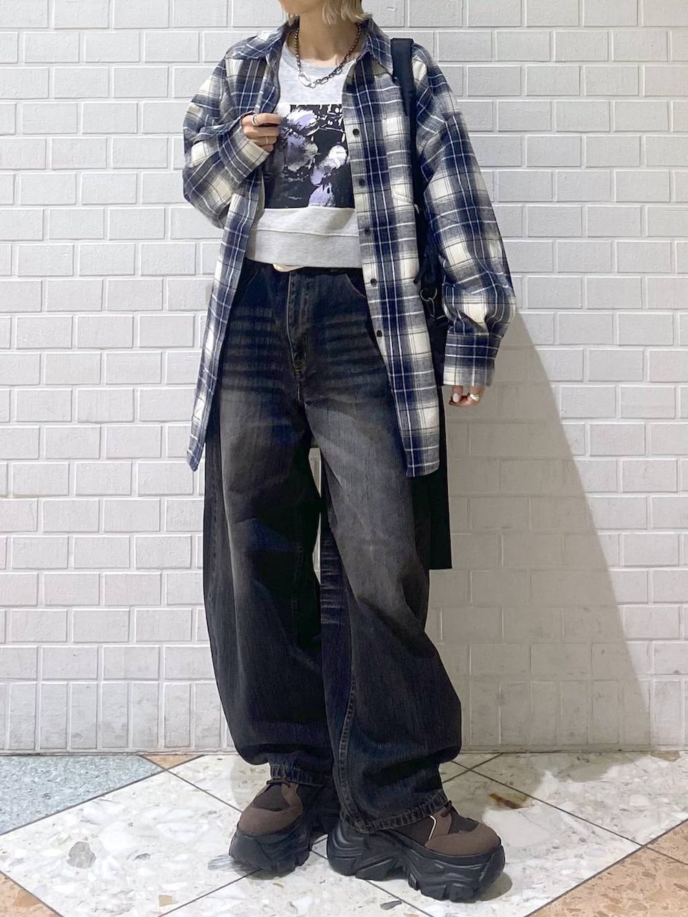 ブラウン系のブーツ、ブラック系のボストンバッグ、ブラック系のデニムパンツを着用したレディースの秋コーディネートの3枚目の写真