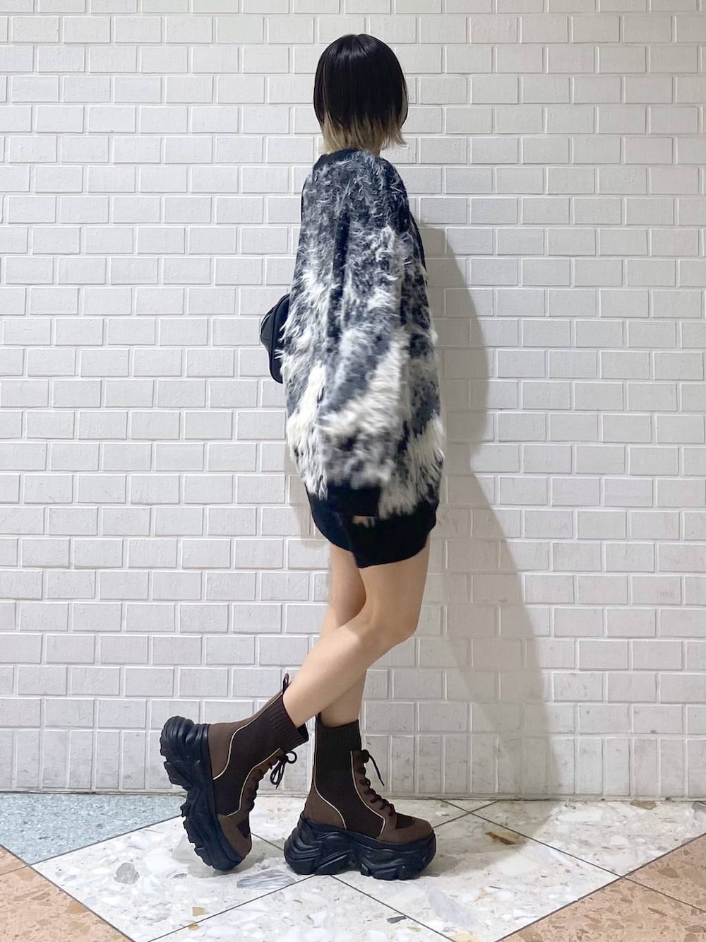 ブラウン系のブーツ、ブラック系のボストンバッグ、レッド系のニット/セーターを着用したレディースの秋コーディネートの7枚目の写真