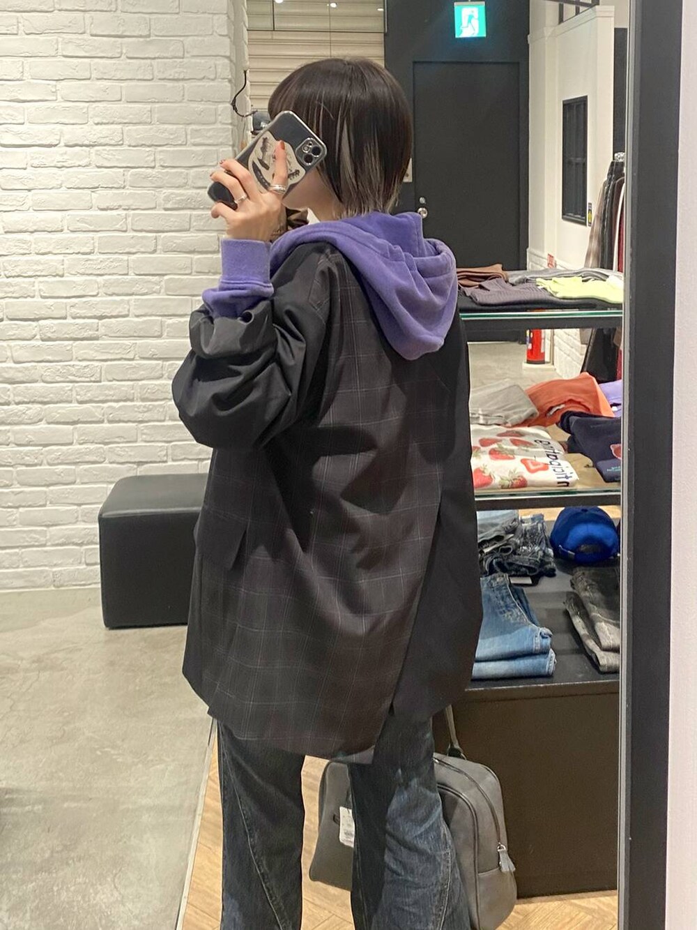 グレー系のボストンバッグ、ブルー系のデニムパンツ、ブラック系のテーラードジャケットを着用したレディースの秋コーディネートの2枚目の写真