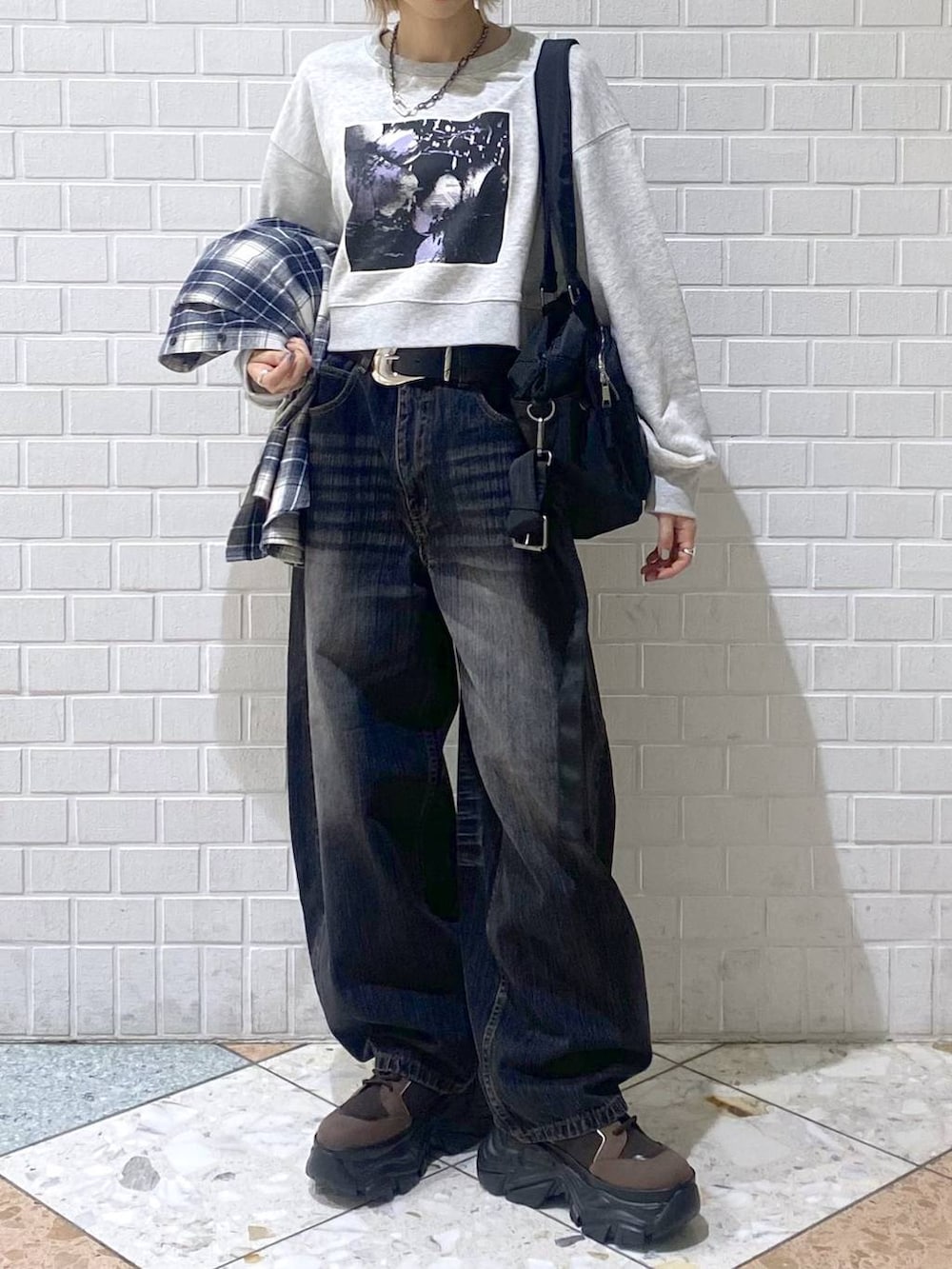 ブラウン系のブーツ、ブラック系のボストンバッグ、ブラック系のデニムパンツを着用したレディースの秋コーディネートの9枚目の写真