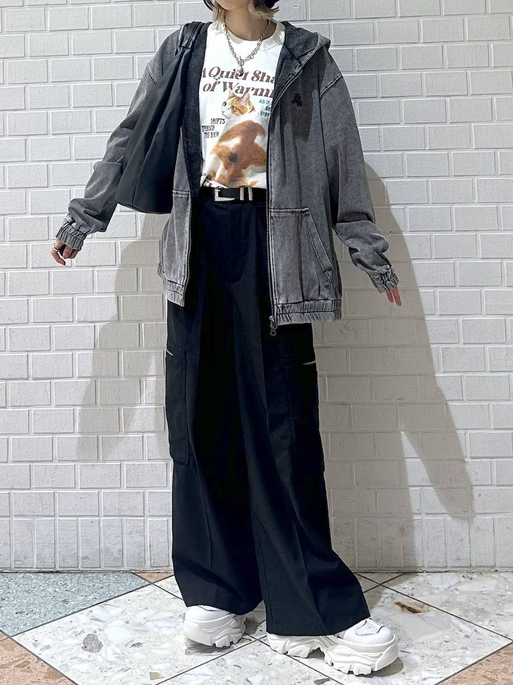 ホワイト系のスニーカー、ブラック系のスラックス、ブラック系のパーカーを着用したレディースの春コーディネートの3枚目の写真